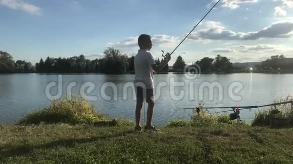 在湖边钓鱼的男孩美丽的鱼塘巴丁附近班斯卡比斯特里察斯洛伐克捕鱼的地方阳光照耀着鱼塘视频的预览图
