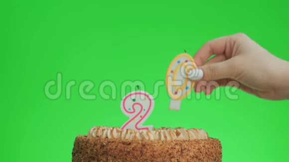 在一个美味的蛋糕上放20号生日蜡烛绿色屏幕20视频的预览图