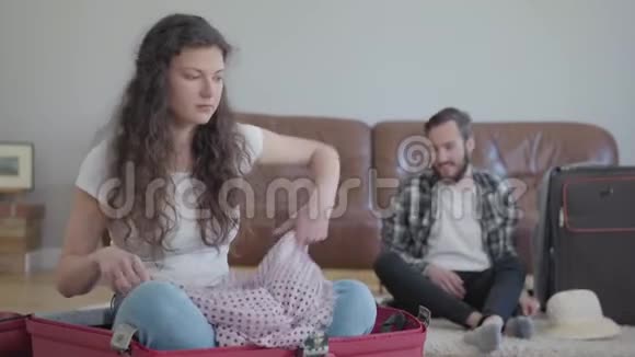 肖像幸福的男人和女人在地板上打包手提箱然后在家旅行妻子把东西扔了坐着视频的预览图
