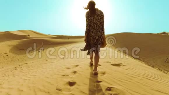 年轻的美女穿着长裙沿着迪拜沙漠的沙丘漫步视频的预览图