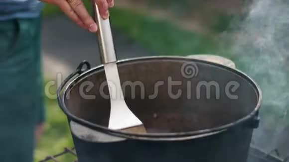 人们在一个大铁锅里搅拌着一个又大又大的厨房铲子菜视频的预览图