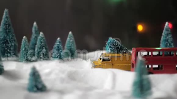 屋顶上有一棵圣诞树的小玩具黄色玩具车慢慢地穿过一个带有雪堆的微型玩具森林视频的预览图
