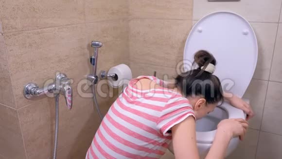 怀孕的年轻疲惫的女人在坐在地板上喝水的厕所里呕吐视频的预览图