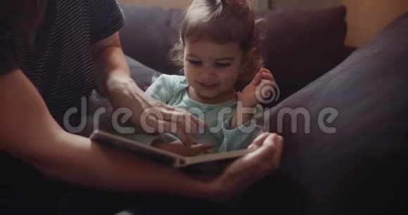 可爱的蹒跚学步的孩子和她妈妈一起读书视频的预览图