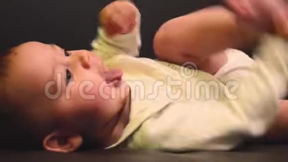近距离拍摄可爱的六个月大的小男孩说话和踢他的脚视频的预览图