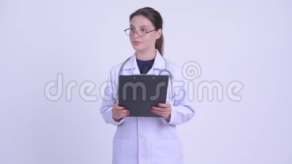 快乐年轻美丽的女医生在剪贴板上看书解释一些事情视频的预览图
