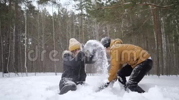 一对夫妇女孩和男人正在冬天的森林里缓慢地互相扔雪视频的预览图
