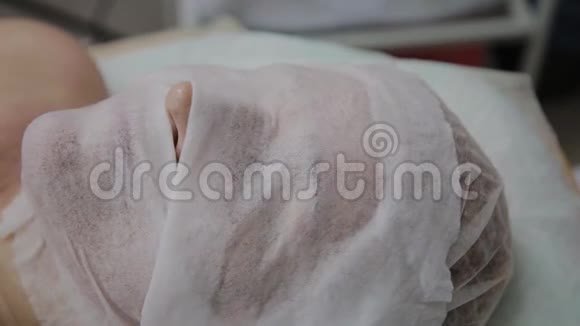 一位躺在美容院的老妇人脸上的保湿湿巾视频的预览图