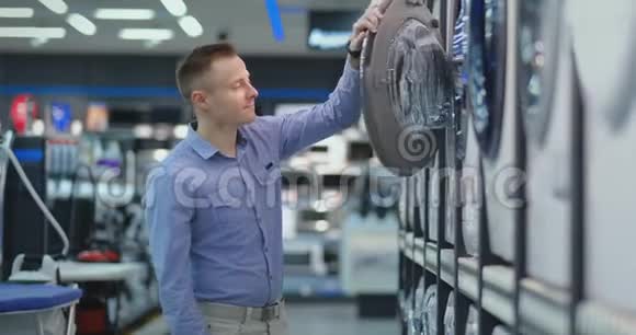 一个年轻的帅哥在一家消费电子商店里选择了一台智能洗衣机作为他的新家研究视频的预览图