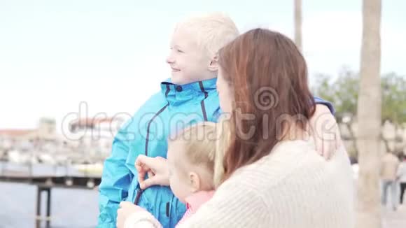 妈妈带着孩子看着大海女儿和儿子拥抱一个女人微笑着视频的预览图
