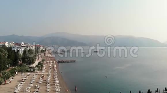 相机沿着地中海的城市海滩海岸飞行空中观景有白色日光浴床和视频的预览图