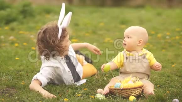 哥哥和哥哥在草地上玩复活节篮子兔子耳朵复活节概念视频的预览图