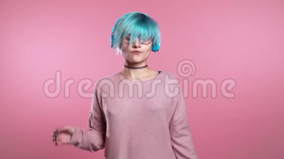 不寻常的女人有蓝色的头发玩得开心微笑戴着耳机跳舞视频的预览图