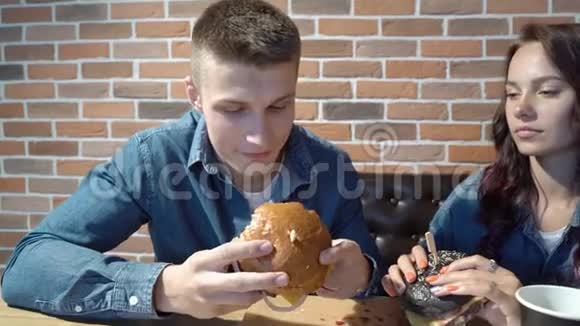 在咖啡馆或家里吃汉堡包的快乐夫妇视频的预览图