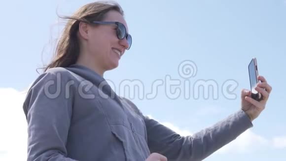 一个女人在手机上对着蓝天拍了一张自拍照片视频的预览图
