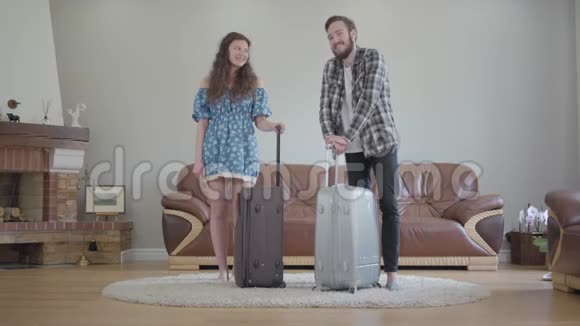 一对幸福的夫妇站在家里的大手提箱的肖像年轻的胡子男和年轻漂亮的女孩视频的预览图