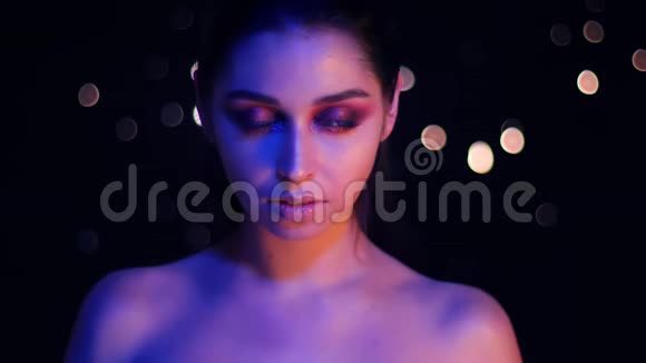 年轻漂亮的白种人女性的特写镜头她身上有紫色的霓虹灯和bokeh背景摆在面前视频的预览图