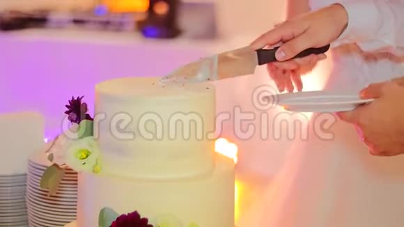新婚夫妇切了一个漂亮的婚礼蛋糕上面装饰着鲜花视频的预览图
