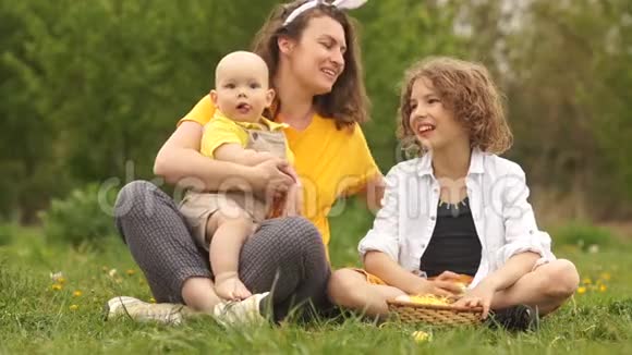 可爱的家人在公园野餐时拥抱复活节家庭快乐妈妈和两个儿子母亲节视频的预览图