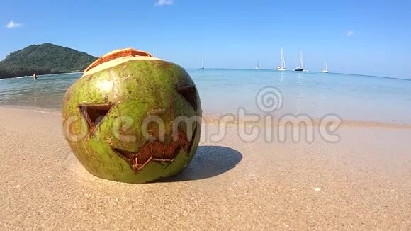 的椰子雕刻着万圣节的脸躺在沙滩上的沙滩上视频的预览图