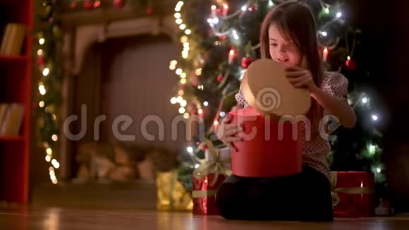 可爱的女孩晚上坐在房间的地板上打开一个礼品盒微笑着视频的预览图