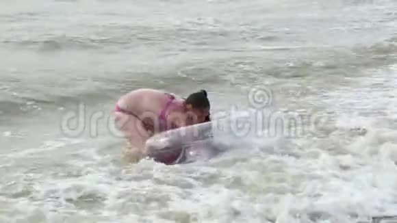 一个充气圈的少女在海浪中游泳视频的预览图