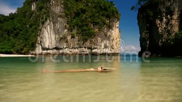 美丽的女孩漂浮在水中的热带海滩上视频的预览图