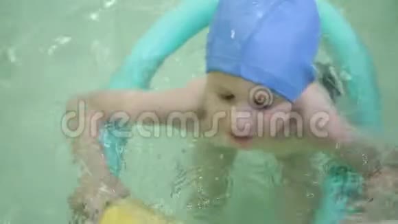 带着橡胶圈的男孩在游泳池里小女孩漂浮在游泳池里的橡胶圈上视频的预览图