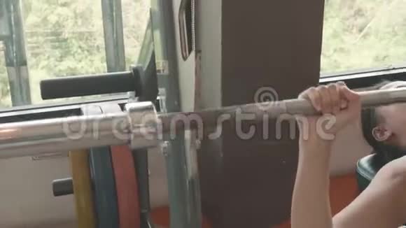 漂亮的亚洲女孩穿着运动服躺在健身长凳上在健身体育训练中心举起杠铃健康视频的预览图