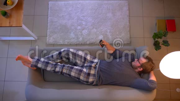 年轻男性躺在沙发上看电视起床在舒适的家中走出家门的特写镜头视频的预览图