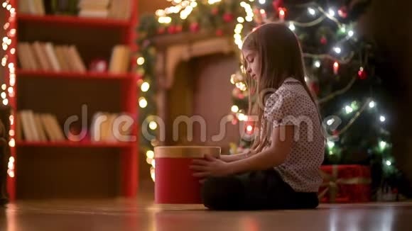 可爱的女孩晚上坐在房间的地板上打开一个礼品盒微笑着视频的预览图