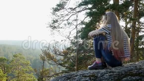 女孩坐在岩石上视频的预览图