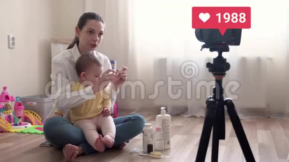 年轻漂亮的妈妈带着宝宝录制vlog或做现场直播带着喜欢的4k电视台视频的预览图