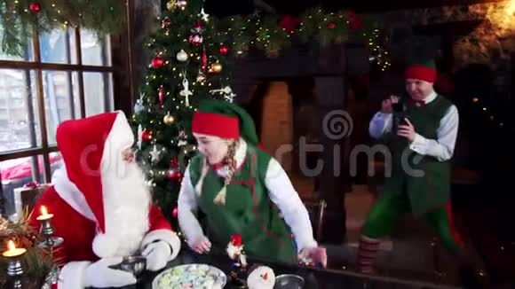 两个精灵和圣诞老人在圣诞背景上拍照视频的预览图