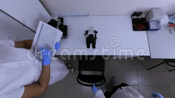 两名实验室助理在一个科学实验室用显微镜工作视频的预览图