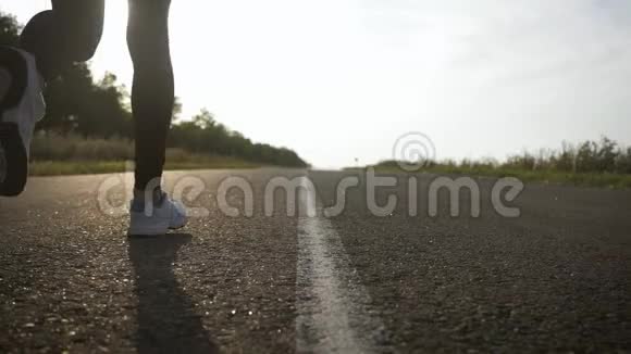 年轻的健身运动女子在日落时在路上跑步运动员跑脚在路上跑动作慢视频的预览图