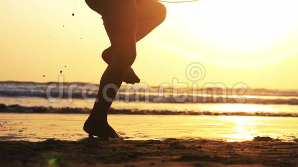 日落时分在海边沙滩上女孩双腿在绳子上跳跃视频的预览图