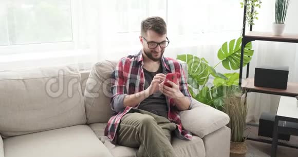 男人在沙发上用手机浏览社交媒体视频的预览图
