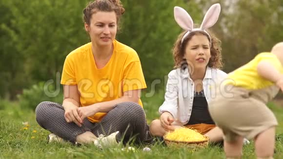 公园里的幼儿扔了一个复活节彩蛋妈妈有一张惊讶的脸快乐的复活节家庭视频的预览图