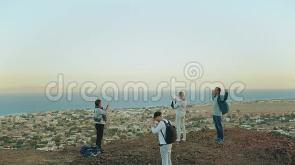 一群朋友在日落时在山顶上放松欣赏海景友谊青春慢动作4k视频的预览图