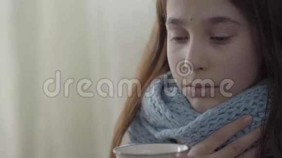 十几岁女孩裹着温暖的围巾手里拿着一杯热茶的肖像3女孩很难过她病了视频的预览图