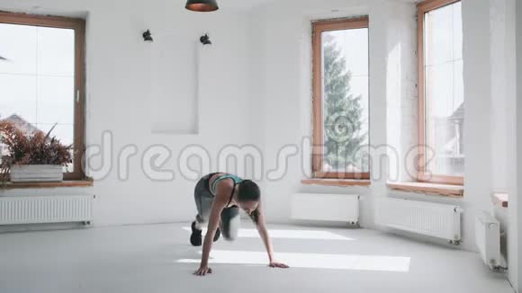 穿着运动装的漂亮女孩在明亮的房间里跑木板视频的预览图