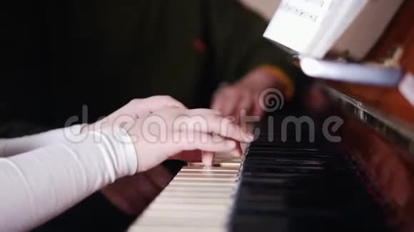 音乐课女孩弹钢琴年长的老师坐在附近和女孩一起玩右侧视图视频的预览图