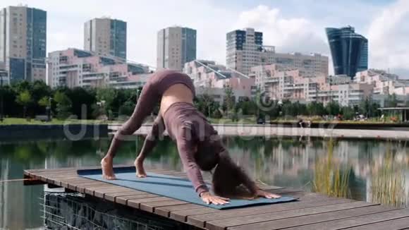 年轻女子做瑜伽运动与城市背景Adhomukhashvanasana视频的预览图