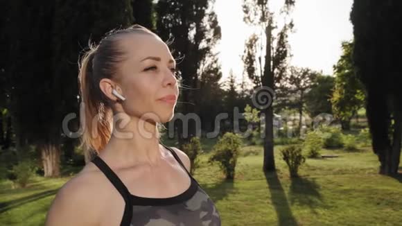 年轻漂亮的女跑步运动员在公园的早操中停下来喝点水视频的预览图