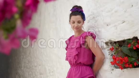 夏天穿着粉色短裙的女孩站在白色的石墙前视频的预览图