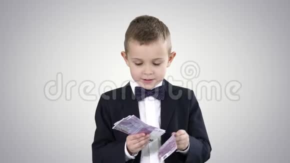 穿西装的小男孩在梯度背景背景下数钱视频的预览图
