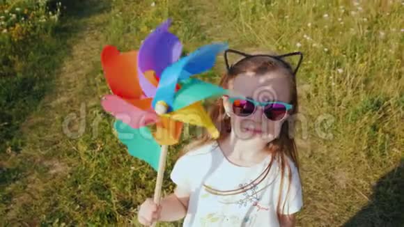 一个手里拿着玩具风车的时髦小女孩的肖像视频的预览图