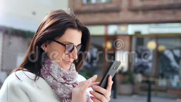 热情的街头时尚微笑的女人在现代城市的特写镜头中使用智能手机在户外聊天视频的预览图