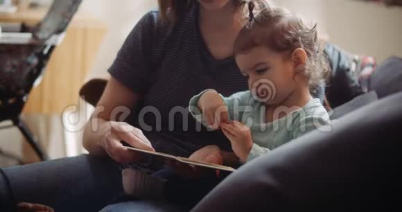 可爱的蹒跚学步的孩子和她妈妈一起读书视频的预览图